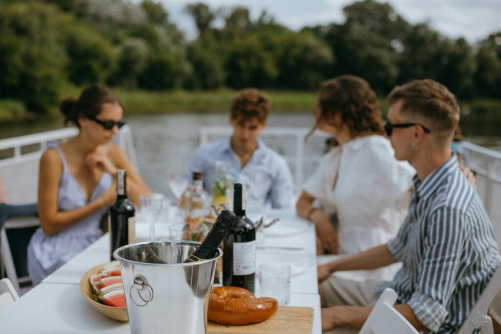 Friends enjoying a relaxing gathering with wine and snacks on a boat during the day.